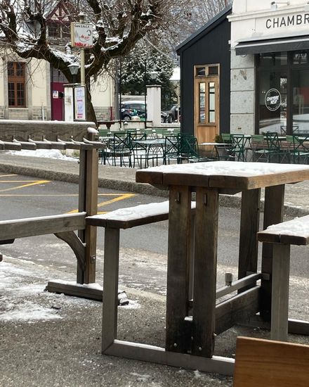 Tall table with bench seats outside, with a dusting of snow on top.