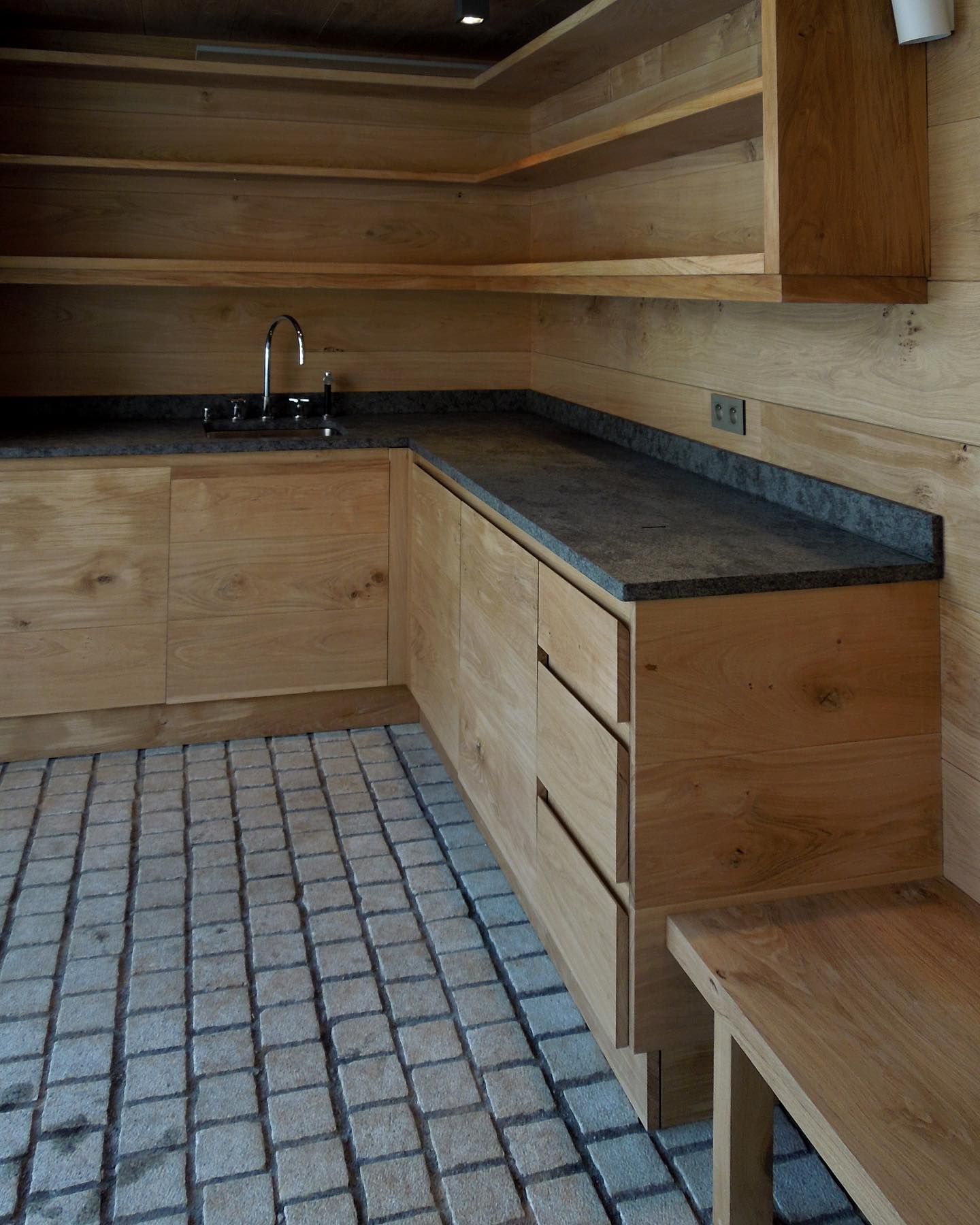 Stone kitchen bench with horisontal wooden drawers and cupboards.