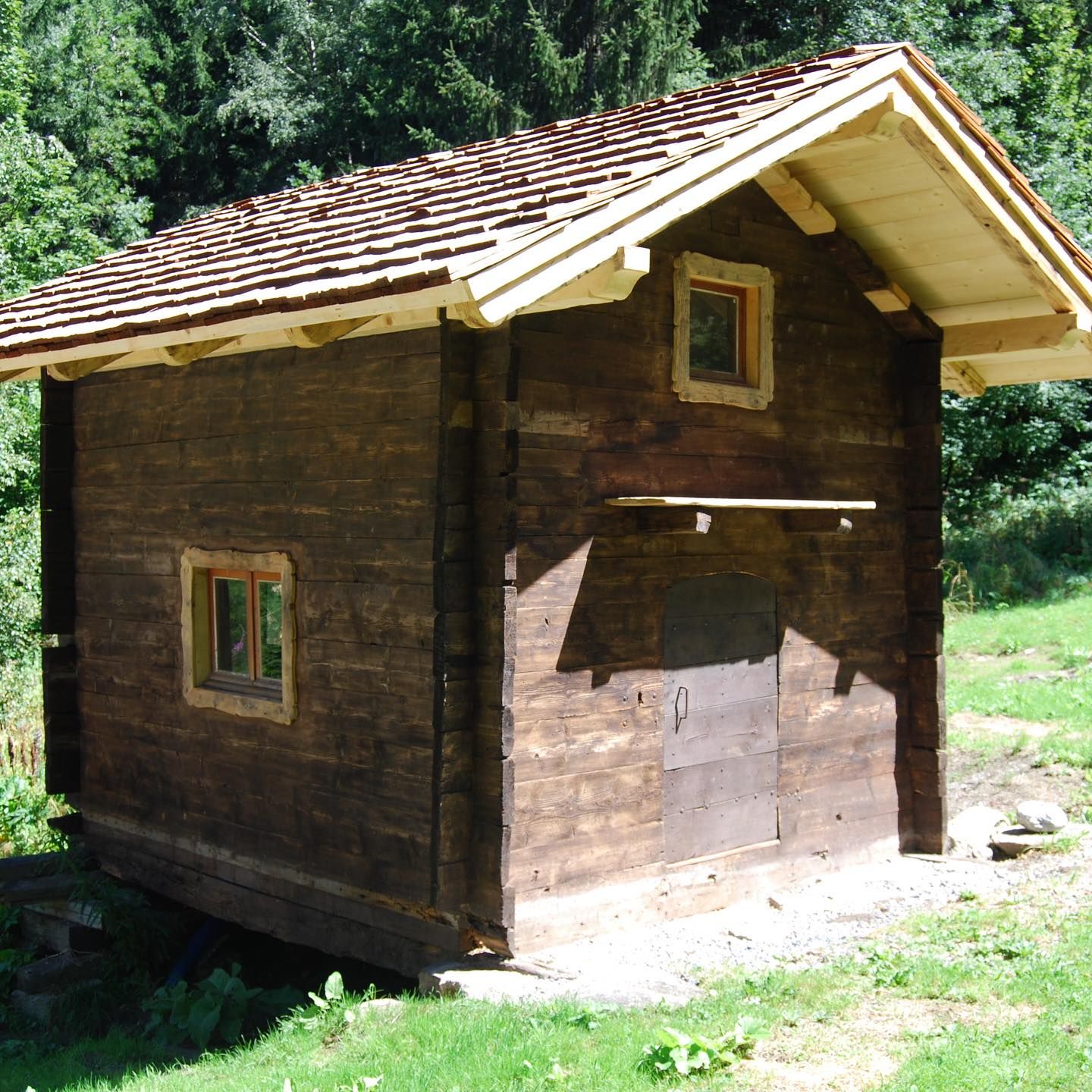 A tiny wooden cabin with windows.