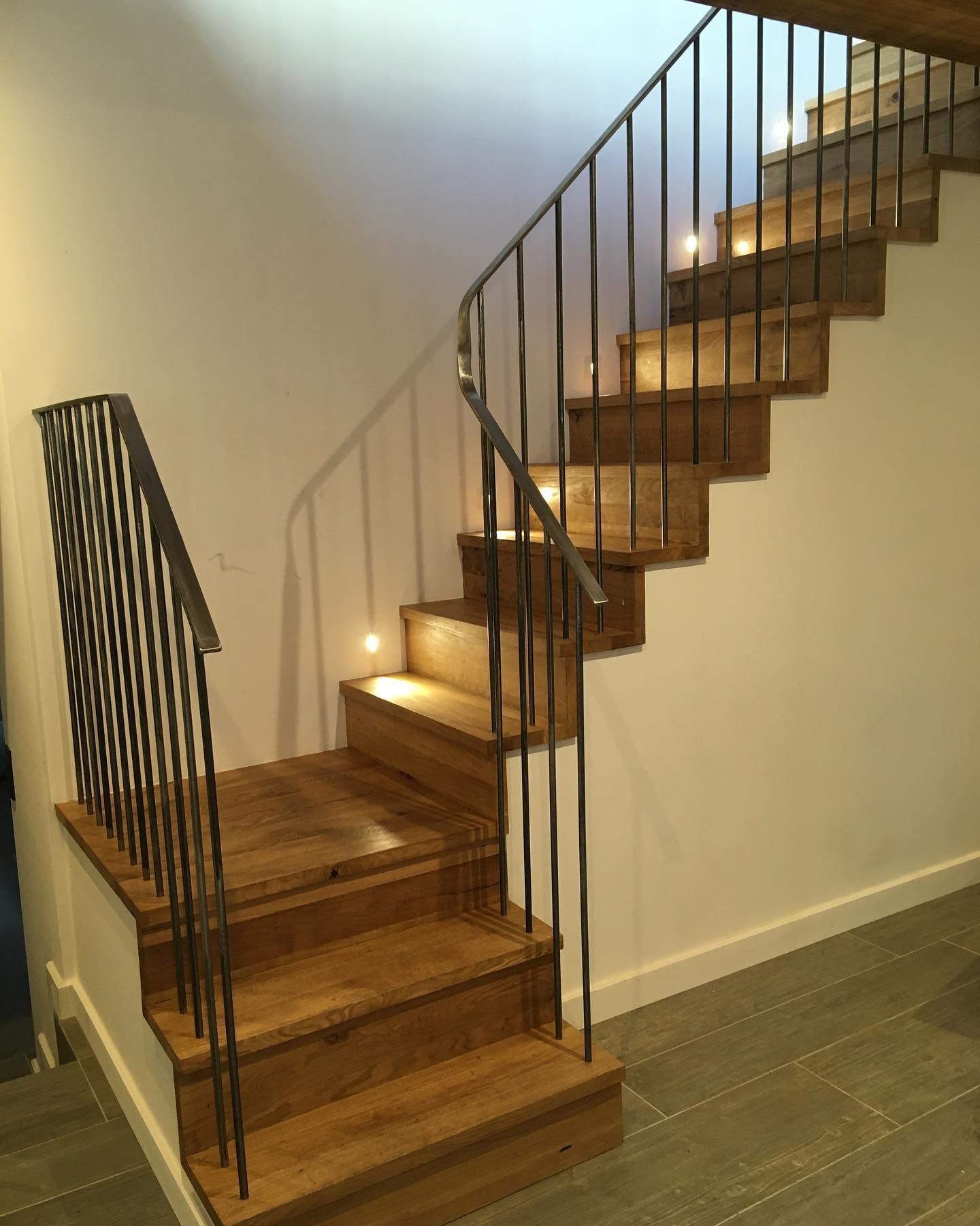 A 90 degree cornered staircase, turning right on the third step. With a thin metal handrail and subtle spot lightening on every second step.